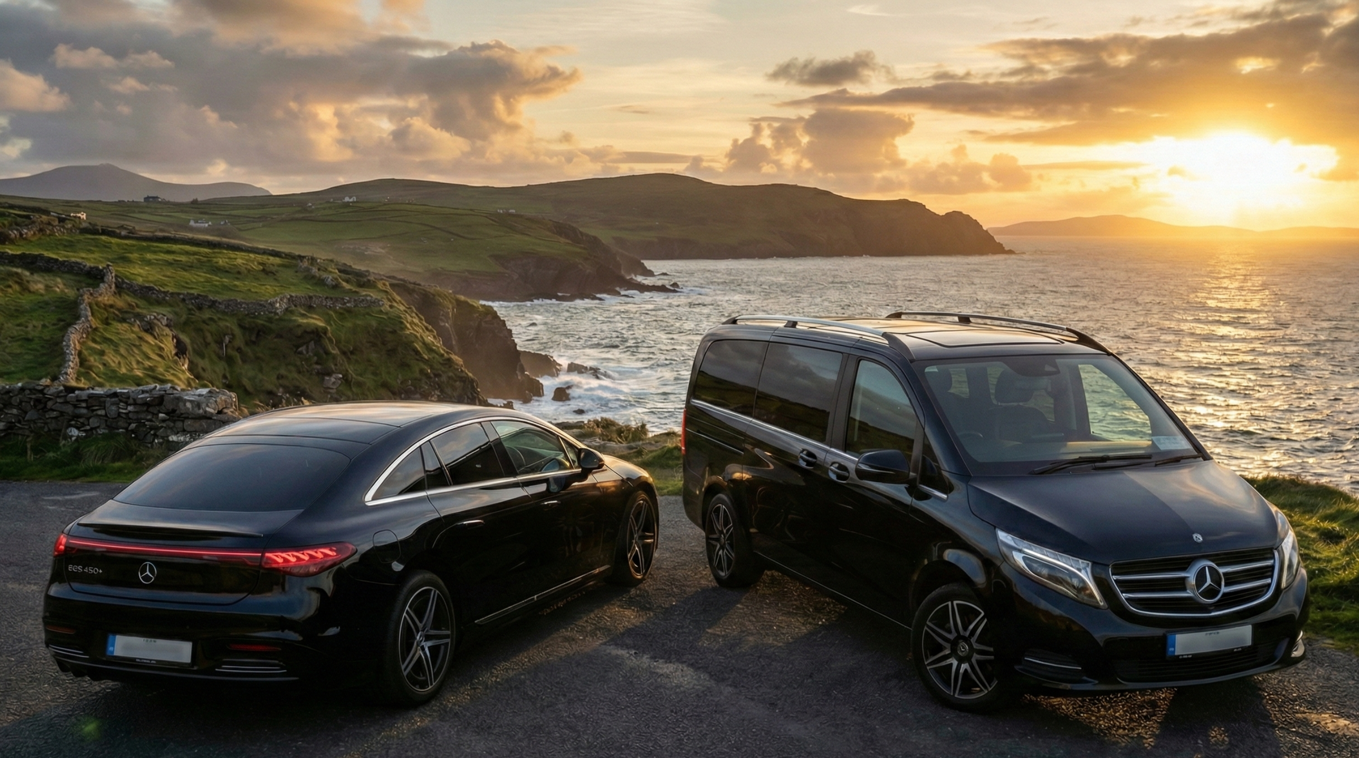 Two Mercedes luxury vehicles - EQS and V-Class - on scenic Irish coastal road at sunset